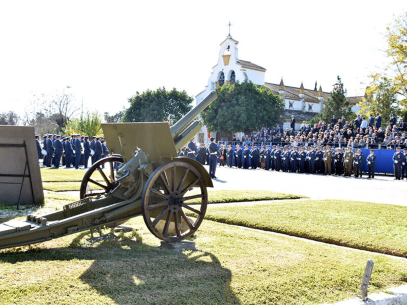Una ceremonia militar con soldados en uniforme frente a una iglesia y un cañón en el centro de la imagen.