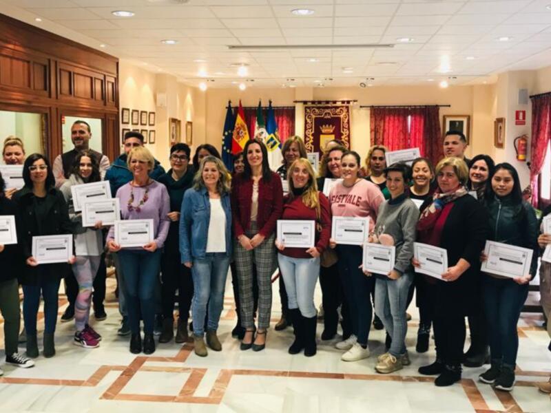 Un grupo de personas posa en un salón con banderas y carteles, celebrando una graduación o certificación.