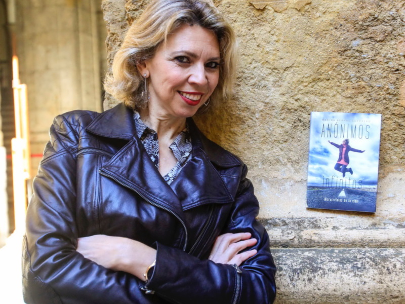 Autora con su libro "Anónimos" en un entorno histórico.