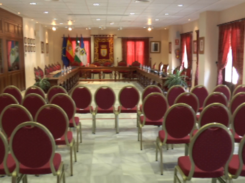Un salón de conferencias con sillas rojas, mesas y banderas.
