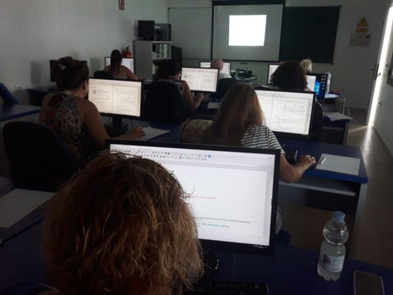 Estudiantes trabajando en computadoras dentro de un aula. La imagen muestra una escena de aprendizaje en grupo, con estudiantes sentados frente a sus computadoras. La iluminación es adecuada para el ambiente de trabajo, y se puede ver una pantalla proyectada en la pared. El aula parece ser un lugar de estudio ordenado y productivo, con todos los estudiantes concentrados en sus tareas.