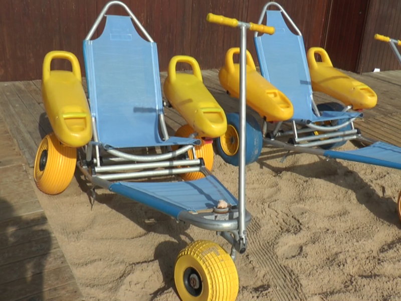 Tres carros de juguete para niños en la arena, con ruedas grandes y asientos azules y amarillos.