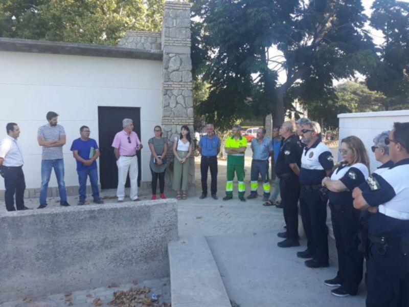 Un grupo de personas, incluyendo policías y trabajadores, se encuentran en una zona con un monumento o estatua de piedra. La escena parece ser parte de una ceremonia o evento formal, con todos los individuos vestidos de manera uniforme. La ubicación es al aire libre, en un área con vegetación y cielo despejado.