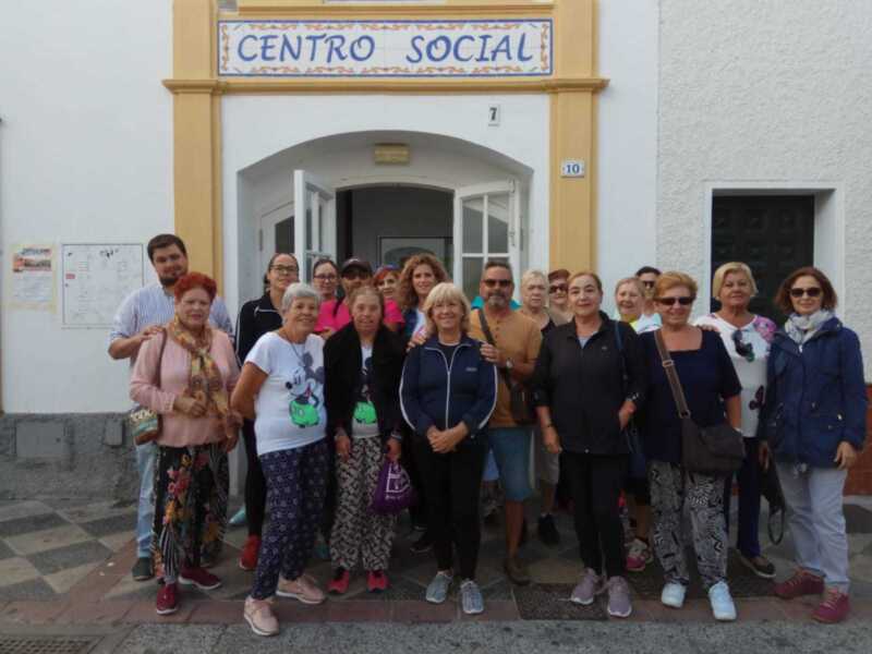 Se observa a un grupo de personas posando frente al Centro Social. La entrada del centro social está decorada con una placa que dice "CENTRO SOCIAL". Los participantes parecen estar disfrutando de la reunión o actividad organizada en este lugar.