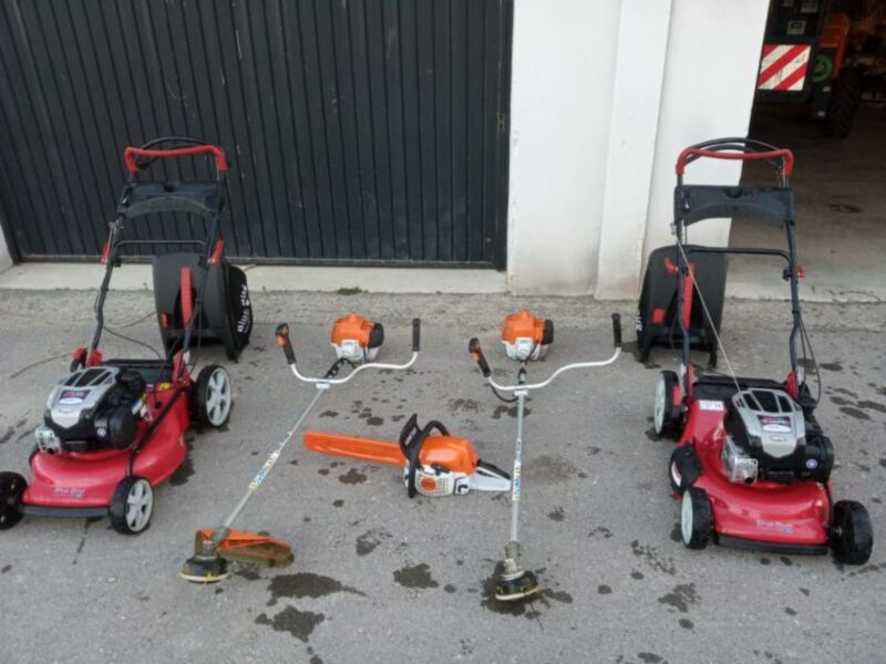 Motosierras y cortacesped de diferentes tamaños, colocados al aire libre en una superficie de hormigón.