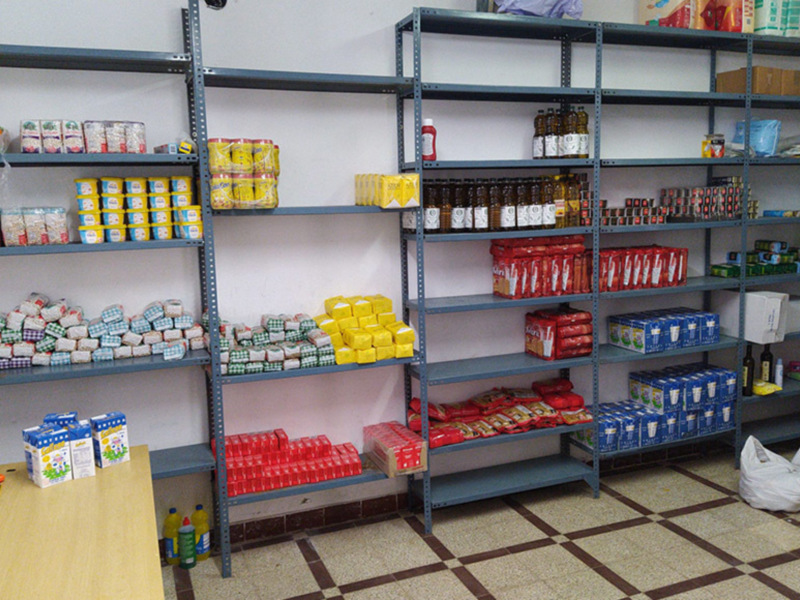 Estanterías de un almacén con productos variados como leche, conservas y botellas de vidrio.