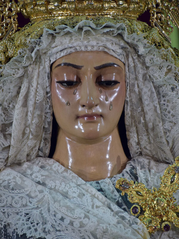 Imagen de una Virgen con vestimentas de luto y una corona dorada, simbolizando la dolorosa soledad de la Virgen María.
