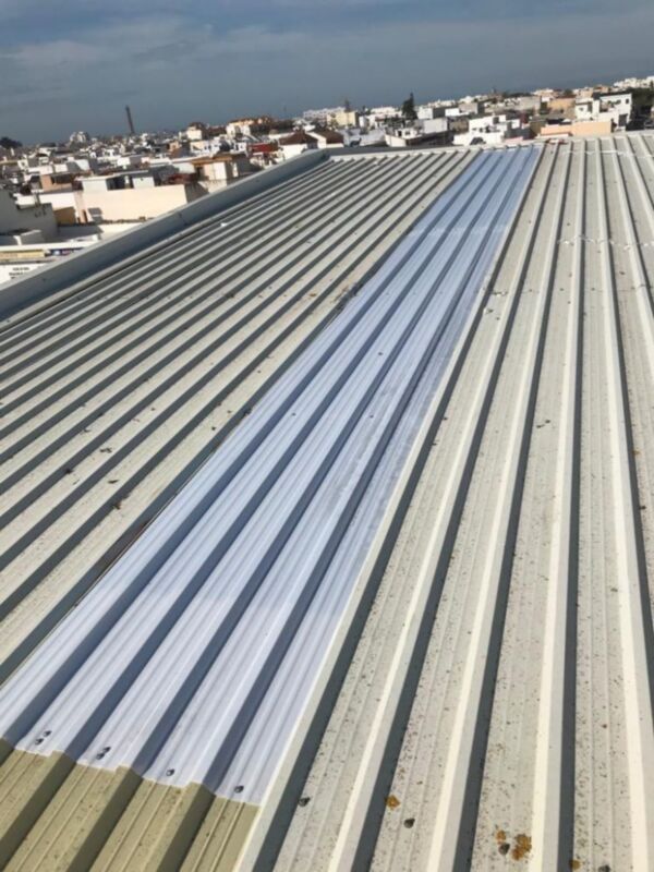 Piso de techo con placas de aluminio en forma de ondas. Fondo urbano con edificios a la distancia.