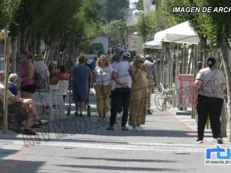 Imagen de archivo de una calle con gente caminando y sillas blancas.