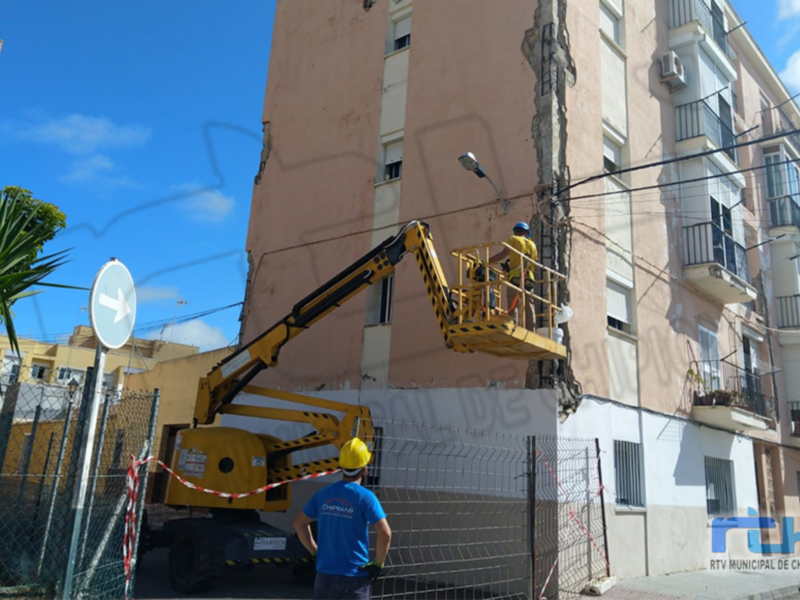 Obras de mantenimiento en un edificio, con una grúa trabajando en la reparación de una fachada.