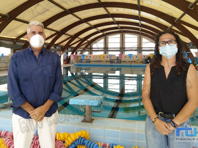 Dos personas con mascarillas en la piscina municipal de Chipiona.