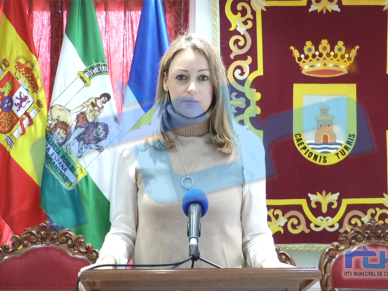 Una mujer habla en un escenario con banderas española y regional en el fondo.