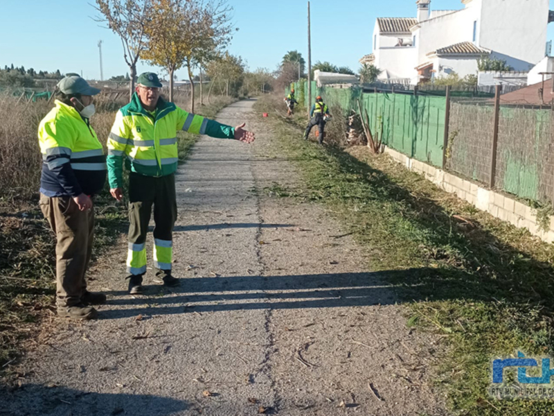 Trabajadores en uniforme de trabajo realizando tareas de mantenimiento en una calle. Imagen muestra detalles de la actividad y el entorno urbano.