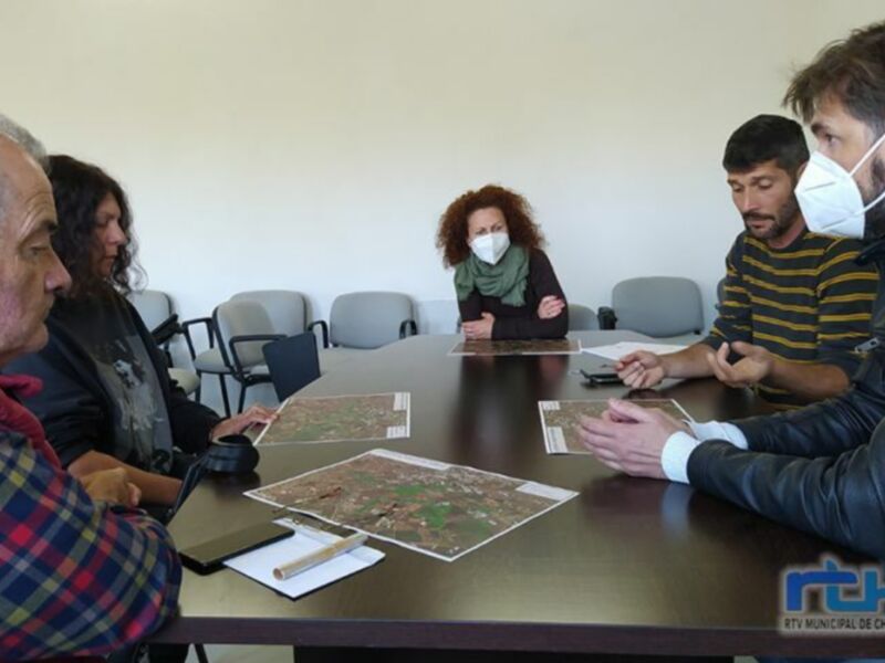 Una reunión de trabajo en una oficina con personas sentadas alrededor de una mesa, mostrando un mapa y discutiendo.