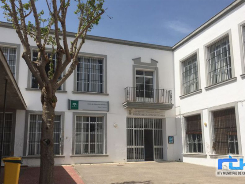 Edificio blanco con ventanas y balcones, en un entorno urbano.