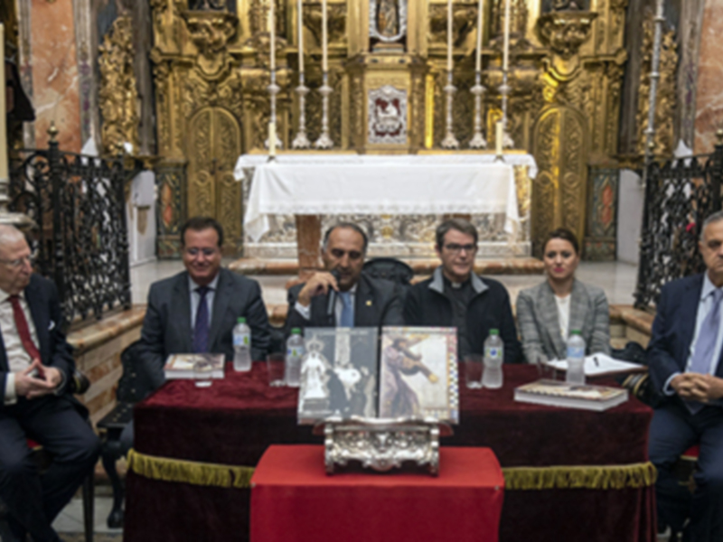 Un grupo de personas sentadas en una mesa en una iglesia, con un altar y vitrales en el fondo.