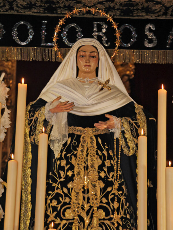 Estatua religiosa con velas encendidas en un ambiente festivo.