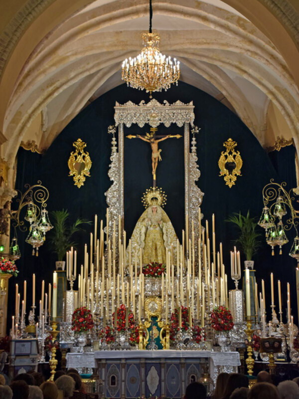 Procesión de la Virgen del Rocío en la iglesia de su santuario, con altares adornados y devotos en el fondo.