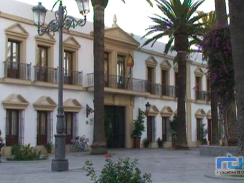 Plaza con palmeras y edificio histórico en Chipiona, España.