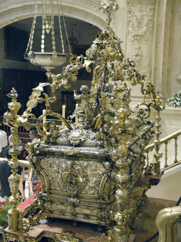 Elegante caja de música dorada con detalles florales y un hermoso candelabro en el techo.