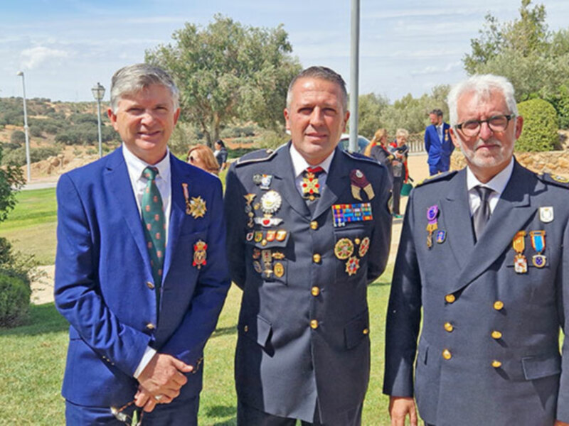 Tres oficiales militares posan para una foto en un entorno verde y relajado, con árboles y césped al fondo.