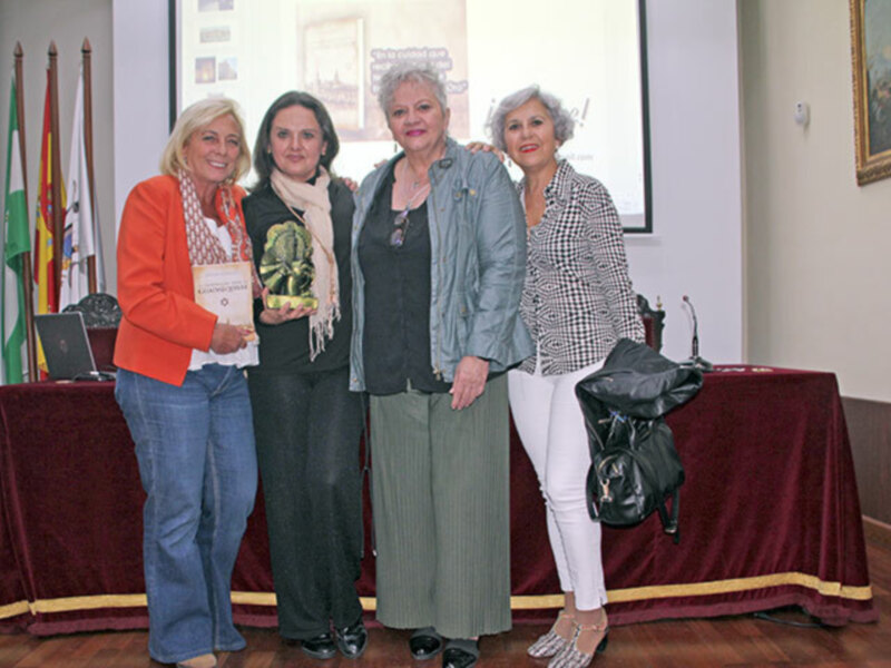 Cuatro mujeres posan juntas en una reunión formal, presentando un libro.