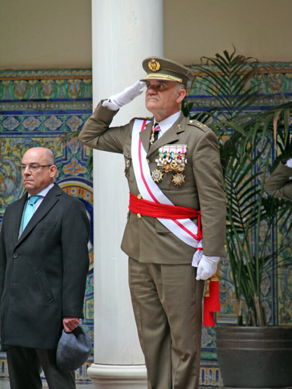 Estatuas de un hombre en uniforme militar y otro en traje formal, frente a un muro de azulejos coloridos.