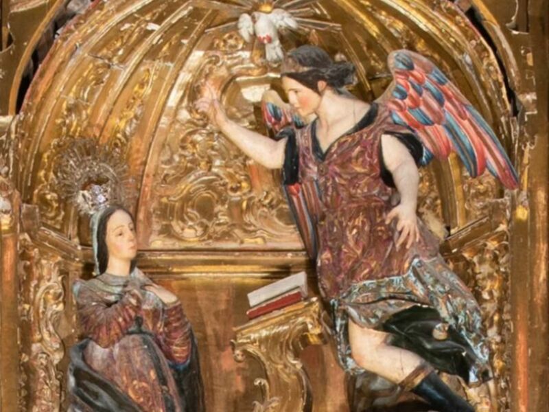 Escultura de madera policromada representando la Anunciación, con un ángel y la Virgen María en un entorno ornamental dorado.